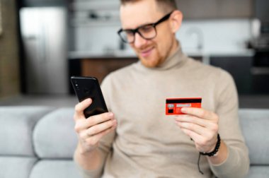 Hipster adamın elinde kredi kartı ve cep telefonu var.