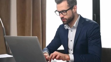 Ciddi şekilde konsantre olmuş sakallı genç bir ofis çalışanı.