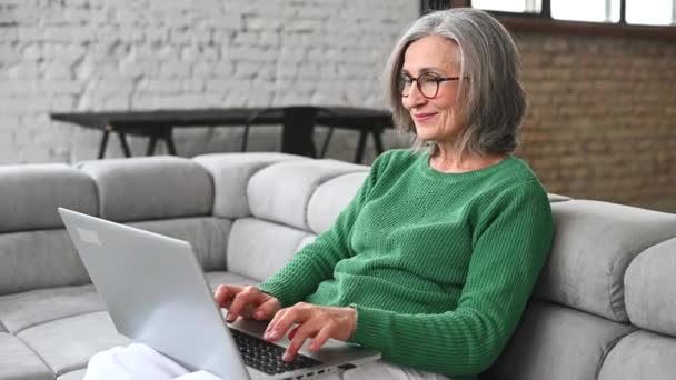 Olgun yaşlı kadın evde dizüstü bilgisayar kullanıyor. — Stok video