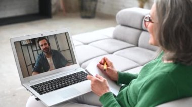Olgun yaşlı kadın evde video görüşmesi için laptop kullanıyor.