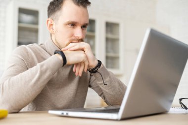 Konsantre iş adamı dizüstü bilgisayarın mutfağında oturuyor.