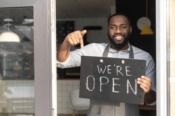 An African-American cafe owner with open sign