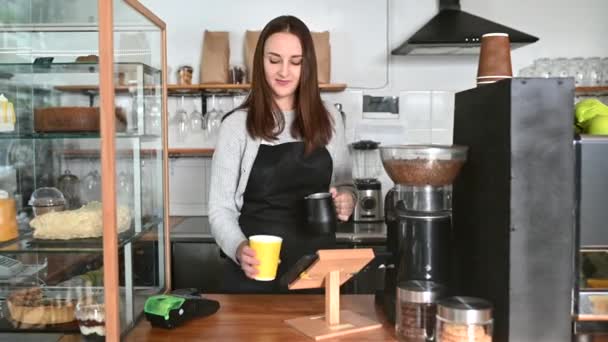 Een serveerster in schort die koffie voordraagt. — Stockvideo