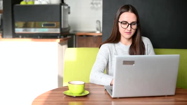 Egy fiatal nő laptoppal a kávézóban. — Stock videók