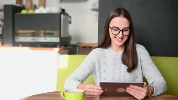 Μια νεαρή γυναίκα με ένα ψηφιακό tablet στο καφέ — Αρχείο Βίντεο