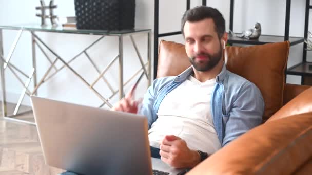 Egy hétköznapi inget viselő fókuszált férfi, aki laptopot használ videohívásra. — Stock videók