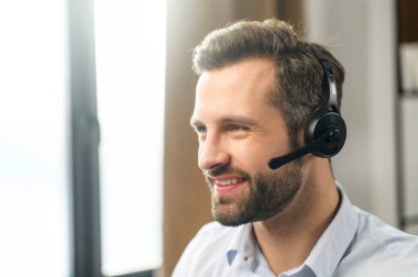 Yakışıklı Avrupalı erkek operatör başka tarafa bakıyor ve kulaklıkla konuşuyor