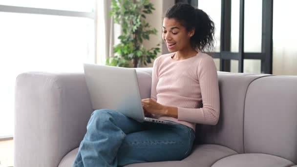 Çekici bir Afro-Amerikalı kadın evde dizüstü bilgisayar kullanıyor. — Stok video