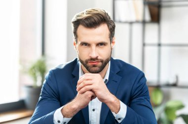 Pahalı takım elbiseli başarılı bir erkek işadamı fotoğraf için poz veriyor.