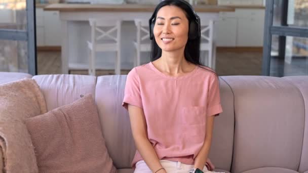 Een aantrekkelijke jonge aziatische vrouw luistert muziek indoor — Stockvideo