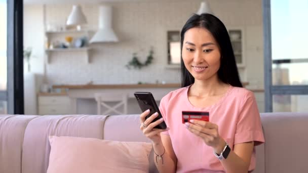 Een aantrekkelijke jonge Aziatische vrouw is met behulp van een smartphone voor online winkelen — Stockvideo