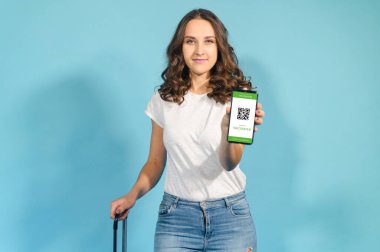 Akıllı telefon ekranında bir kadın renkli pasaport gösteriyor.