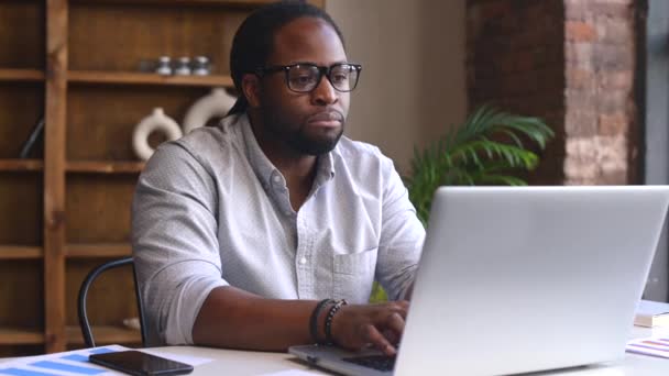 Triste joven afroamericano empleado masculino usando una computadora portátil — Vídeos de Stock