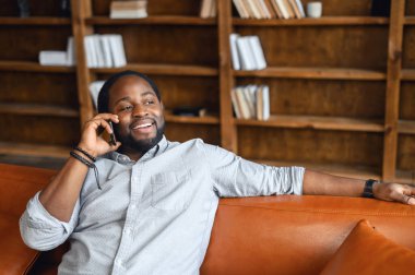 Rahat bir Afrikalı Amerikalı cep telefonuyla konuşuyor.