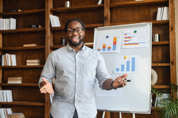 Giovane insegnante afroamericano spiegando grafici — Foto Stock