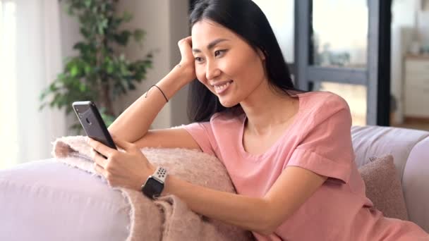 Una atractiva joven asiática mujer está utilizando un teléfono inteligente interior — Vídeo de stock