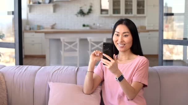 Een aantrekkelijke jonge aziatische vrouw is met behulp van een telefoon voor video oproep — Stockvideo