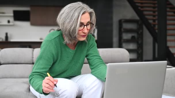Ώριμη ηλικιωμένη γυναίκα χρησιμοποιεί ένα φορητό υπολογιστή στο σπίτι — Αρχείο Βίντεο
