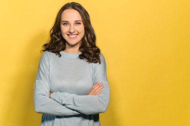 Sarı arka planda poz veren çekici bir kadın.