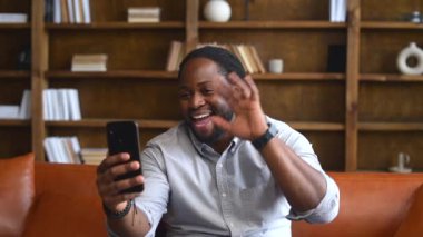 Video görüşmesi için telefon kullanan Afro-Amerikalı bir ofis çalışanı.