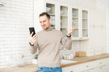 Akıllı genç adam video görüşmesi için akıllı telefon kullanıyor.