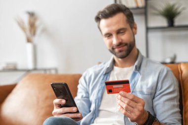 Elinde kredi kartı ve cep telefonu olan hippi bir adam.