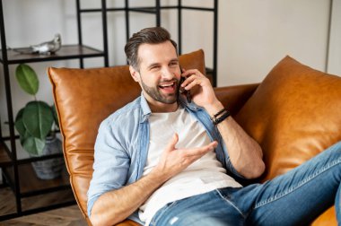 Genç milenyum sakallı adam cep telefonuyla konuşuyor.