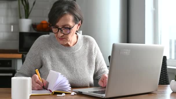 Idősebb nő, aki laptopot használ otthon, távolról dolgozik — Stock videók