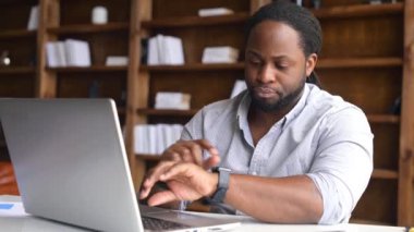 Akıllı Afro-Amerikalı dizüstü bilgisayar kullanıyor ve zamanı kontrol ediyor