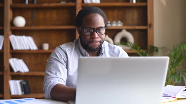 Afro-Amerikaanse mannelijke kantoormedewerker met behulp van een laptop voor werk — Stockvideo