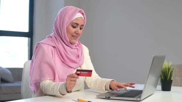 Mujer musulmana usando hijab usando portátil para compras en línea en la oficina — Vídeos de Stock