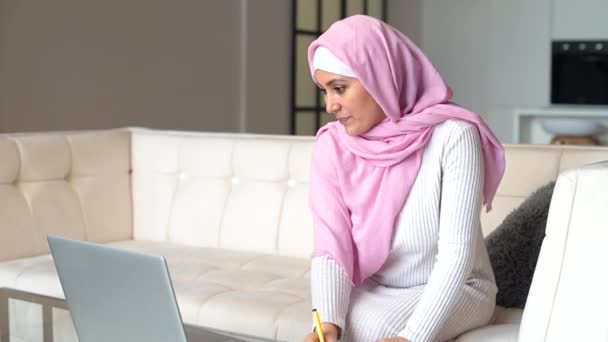 Μουσουλμάνα γυναίκα που φοράει μαντίλα χρησιμοποιώντας φορητό υπολογιστή στο σπίτι — Αρχείο Βίντεο