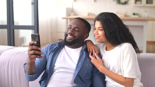 Feliz casal multirracial usando um smartphone em casa — Vídeo de Stock