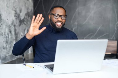 Gülümseyen Afro-Amerikan adam video araması için laptop kullanıyor.