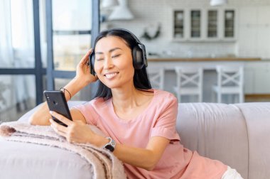 Kulaklık takan çekici bir Asyalı kadın müzik dinliyor.