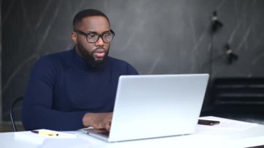 Kapalı alanda dizüstü bilgisayar kullanan Afro-Amerikalı bir çalışan.