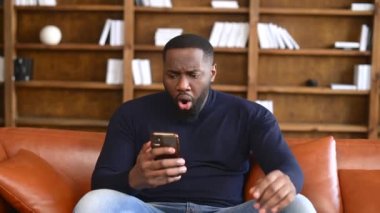 Kapalı alanda akıllı telefon kullanan Afro-Amerikan erkek çalışan.