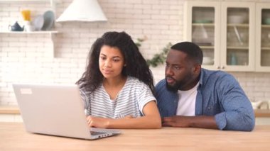 Evde dizüstü bilgisayar kullanan çok ırklı bir çift.