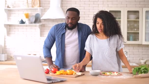 Feliz casal multirracial preparar refeição juntos na frente de um laptop — Vídeo de Stock