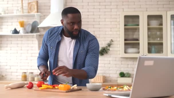 Uomo afro-americano guardando video tutorial di cucina sul computer portatile — Video Stock