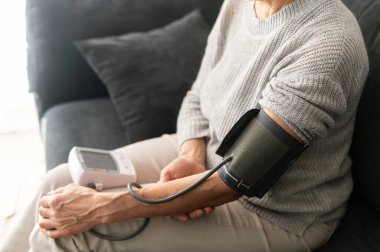 Evde kan basıncını ölçen yaşlı bir kadın..