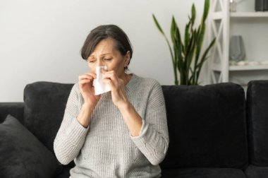 Yaşlı bir kadın evde hapşırıyor.