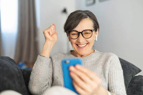 Charming senior woman using smartphone at home