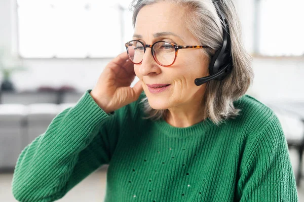 Hermosa mujer mayor con auriculares toma una llamada — Foto de Stock