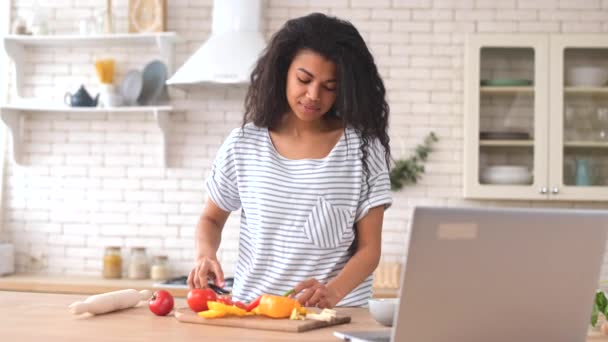 Bájos biracial nő néz főzés videó bemutató a laptopon — Stock videók