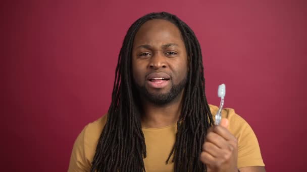 Alegre afro-americano cara escovação dentes isolado no vermelho fundo — Vídeo de Stock