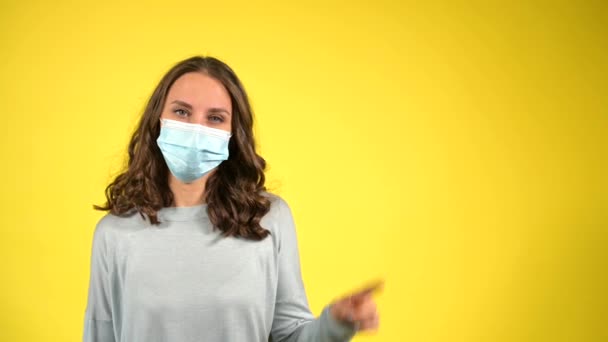 Vonzó göndör fiatal viselő arc maszk elszigetelt sárga — Stock videók