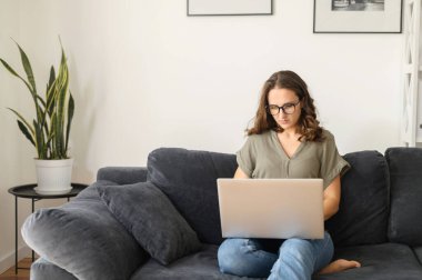 Evde dizüstü bilgisayar kullanan çekici kıvırcık kadın.