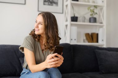 Evde akıllı telefon kullanan çekici kıvırcık kadın.