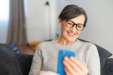 Evde akıllı telefon kullanan çekici bir son sınıf kadını.